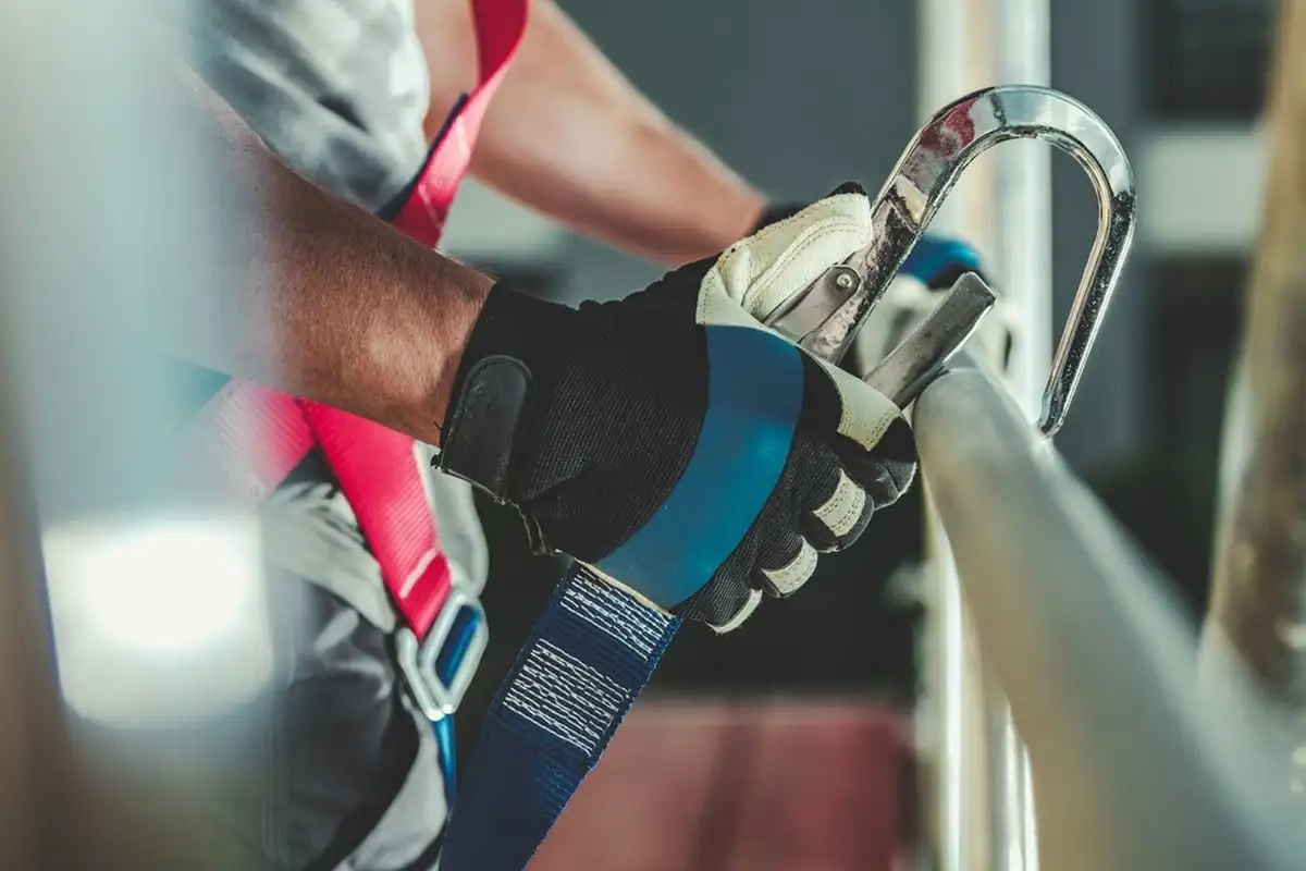 Gloved hand clipping a karabiner onto a rail